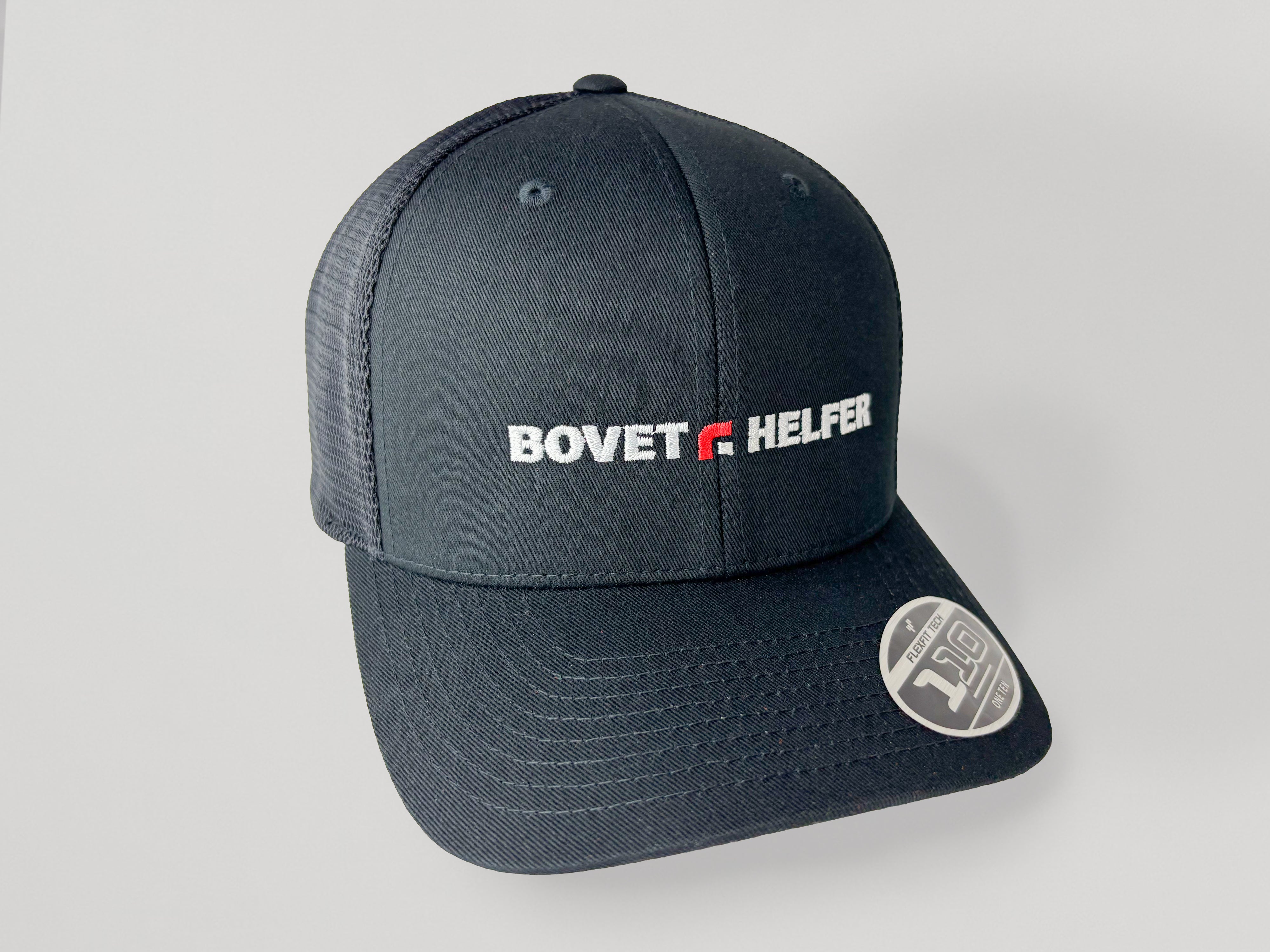 Casquette noire brodée Bovet+Helfer en blanc et rouge, visière incurvée, sur fond gris uni.